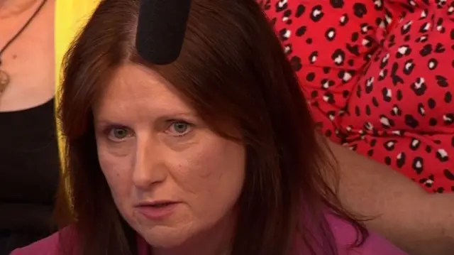 Woman in audience wearing red with a black microphone being held over her head