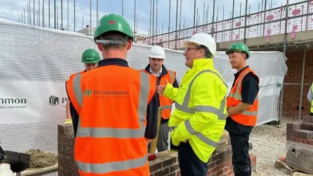 Keir Starmer in yellow hi-vis jacket speaking to workers at construction site