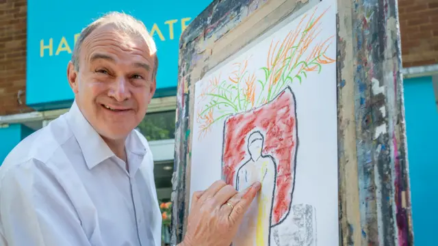 Sir Ed Davey drawing a charcoal on pastel artwork