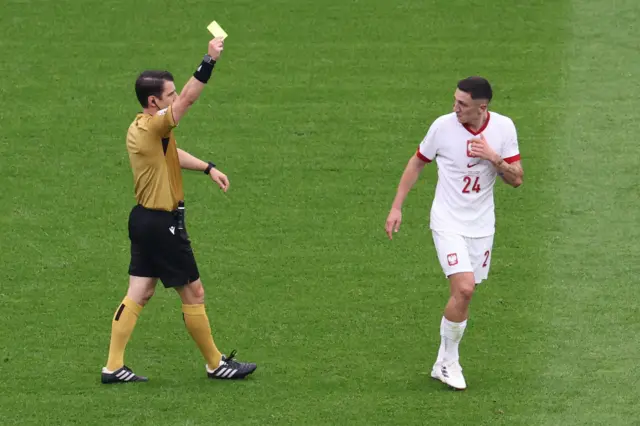 Turkish referee Umut Meler shows the yellow cared to Bartosz Slisz of Poland