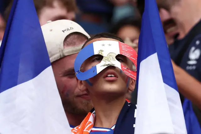 Child wears a tricolour mask in homage to Mbappe