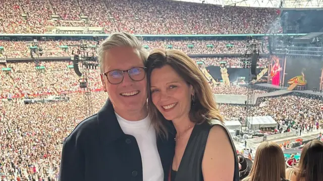 Keir Starmer poses for a photograph with his wife in an arena