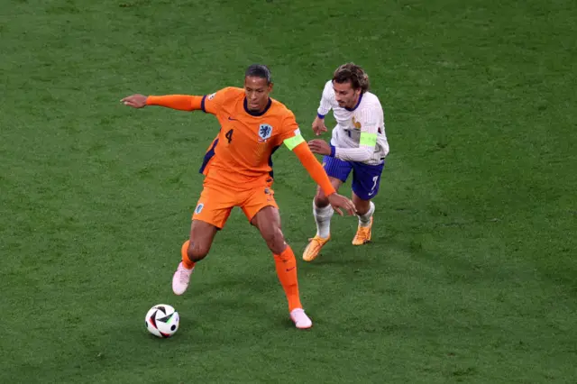 Virgil van Dijk on the ball with Antoine Griezmann close behind