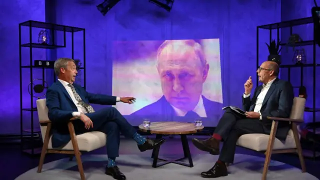 Nigel Farage sits down with Nick Robinson with a picture of President Putin between them.