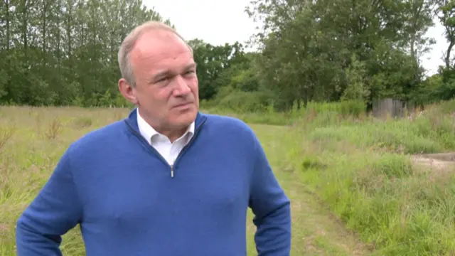 Ed Davey is seen taking questions in a farmer's field.