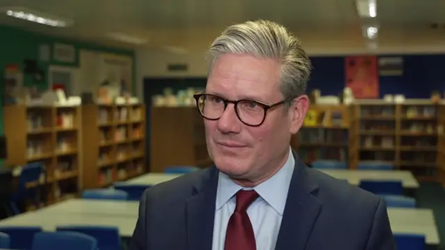 Sir Keir Starmer answers a reporter's question while in a classroom.