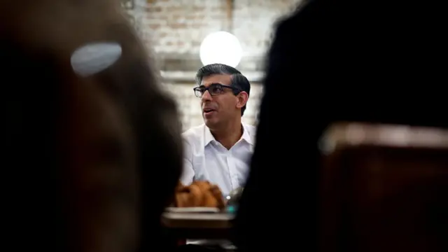 Rishi Sunak is seen close up while he sits at a table.