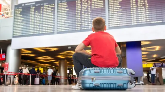 Boy sitting on suitcase in airport