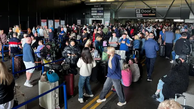 Passengers queue outside the Manchester Airport.