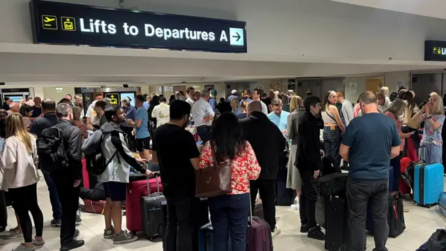 Passengers queue outside Terminal 1 after an overnight power cut led to disruptions and cancellations at Manchester Airport in Manchester, Britain, June 23, 2024