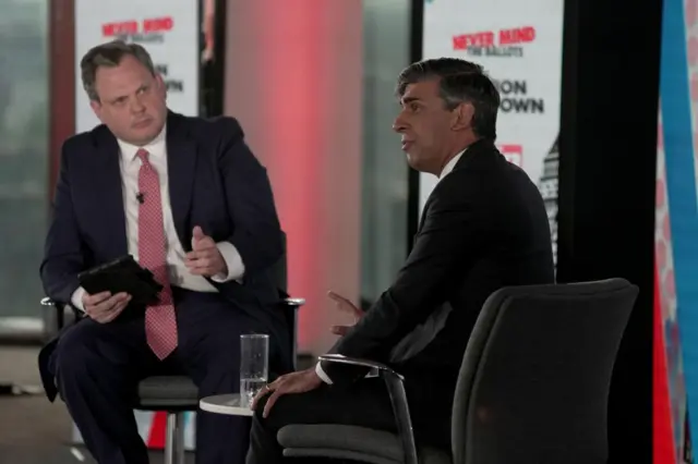 Rishi Sunak answering questions at The Sun's election Q&A, he is sat in the foreground of the image, next to Harry Cole