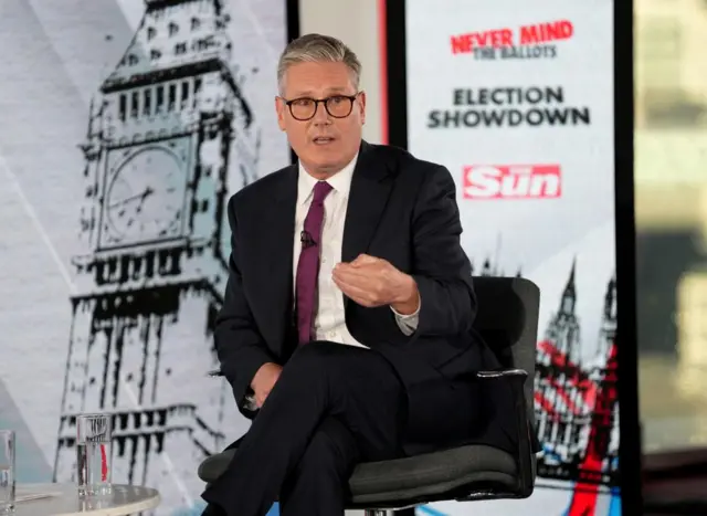 Keir Starmer sat onstage at The Sun's Q&A event, there is a branded banner behind him