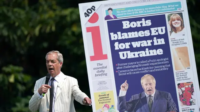 Nigel Farage speaks in front of a blow-up image of a front page of the i newspaper