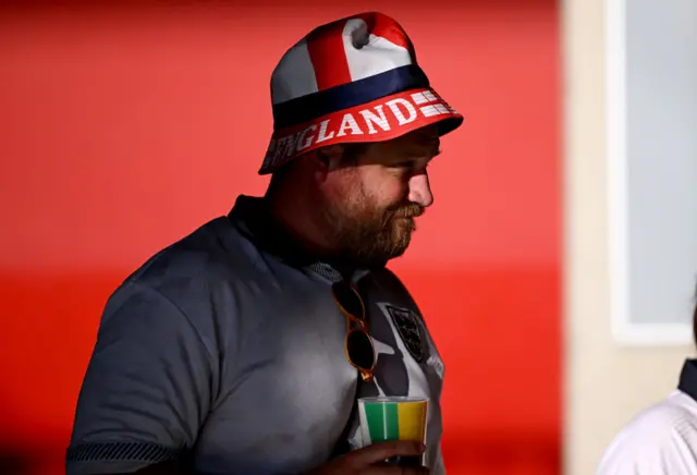 England fan holds a pint of beer while wearing a bucket hat