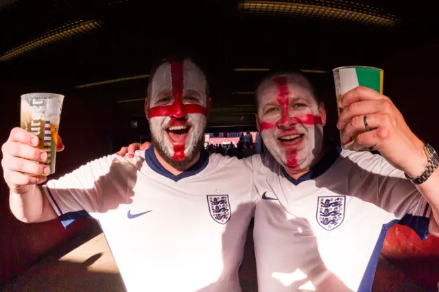 England fans painted as the flag of St George pose with beers