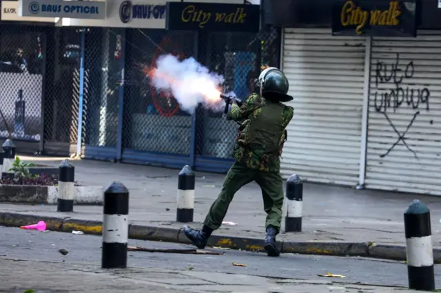 A police officer fires teargas at demonstrators