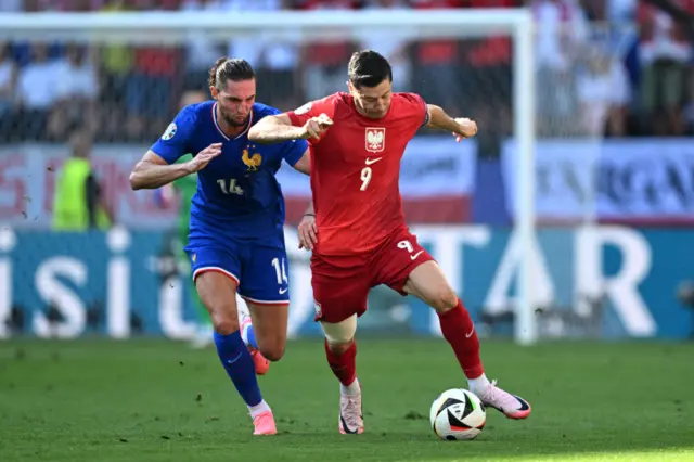 Robert Lewandowski of Poland is challenged by Adrien Rabiot of France