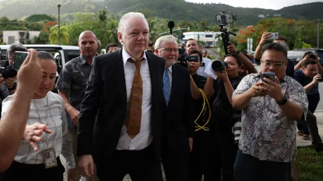 Julian Assange flanked by journalists