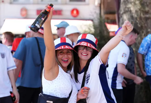 Two England fans hold bottles of beer in the air