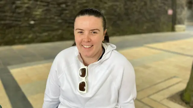 Orla, a female sitting down and wearing a white hoody