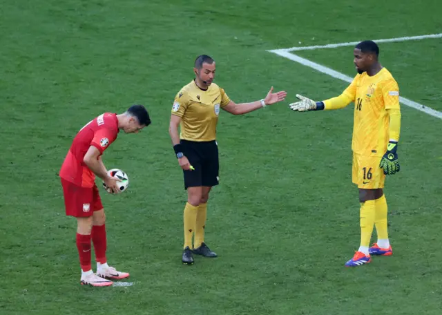 Robert Lewandowski of Poland, referee Marco Guida, and France goalkeeper Mike Maignan prepare for a penalty