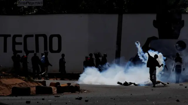 A protester throws a tear gas canister back at police