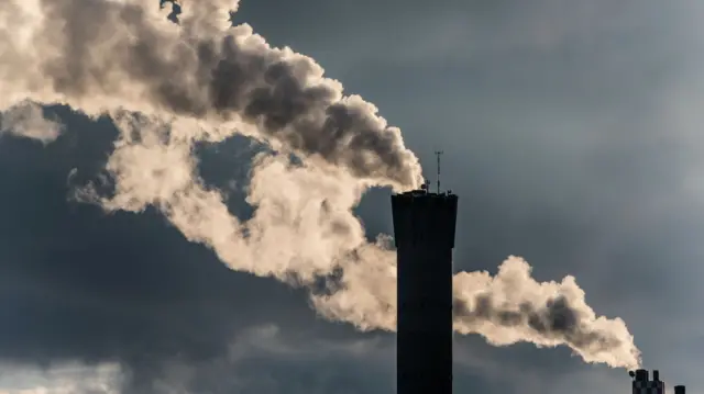 Dense smoke is leaving a smoke stack of a power plant