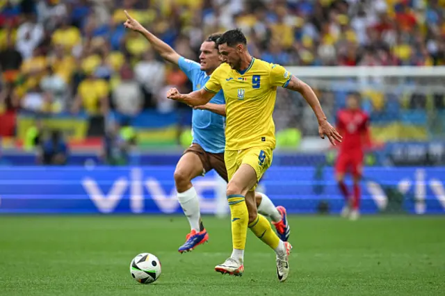 Roman Yaremchuk runs with the ball past Belgium's defender #04 Wout Faes