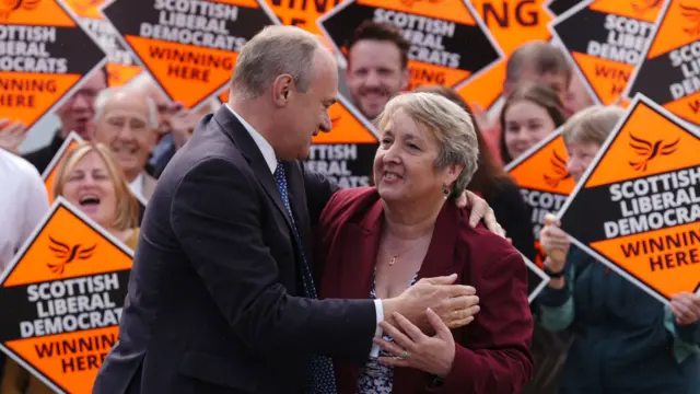 Lib Dems Ed Davey and Christine Jardine embrace in front of Lib Dem supporters