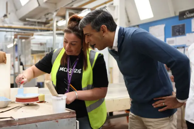 Rishi Sunak watches an employee demonstrate painting technique at a ceramics business in Stoke-on-Trent