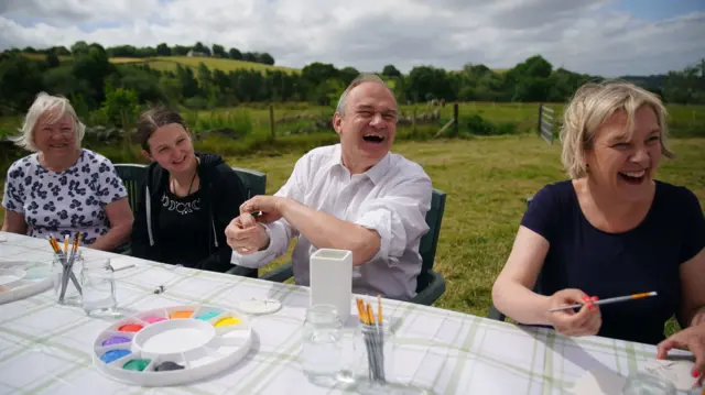 Davey at a table laid with paints against a countryside backdrop