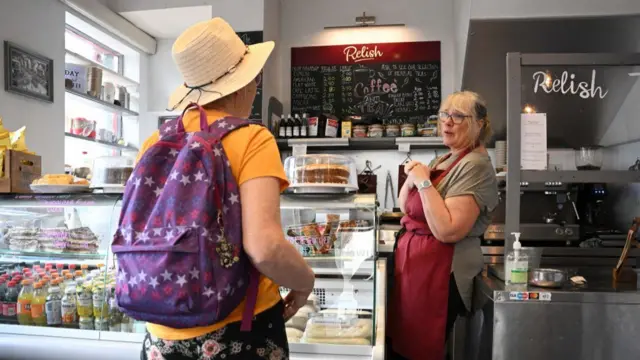 A cafe owner talks to a customer in a shop