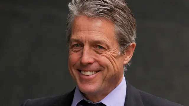 Hugh Grant smiles for a photograph taken in April