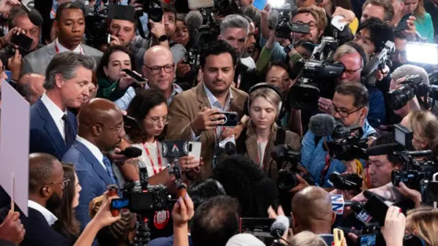 Gavin Newsom (far left, in blue suit) and Democratic Senator Raphael Warnock take questions in the spin room