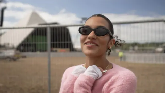 Olivia Dean stands in front of the Pyramid Stage at Glastonbury Festival