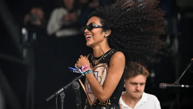 Singer Olivia Dean smiles as she walks across the stage.