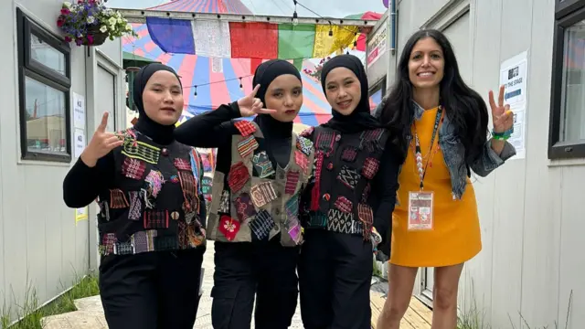 Members from the band Voice of Baceprot pose in a picture, dressed in hijabs with black outfits and colourful vests with patches on top.