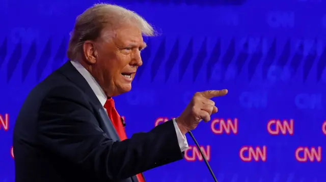 Donald Trump points while answering a question at the debate