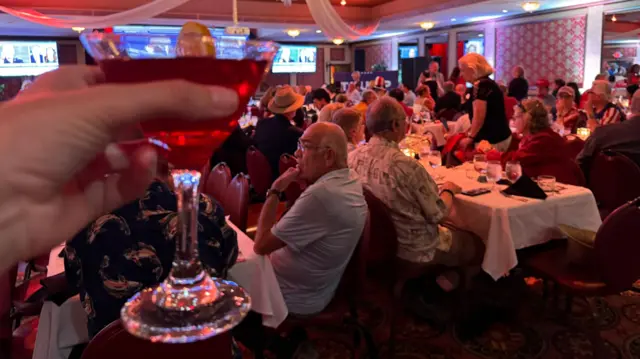 A hand holds up a drink at a party