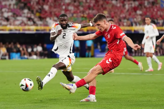 Joakim Maehle attempts a shot on goal under pressure from Germany's Antonio Rudiger