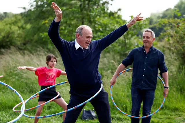 Lib Dem leader Ed Davey and Scottish Lib Dem leader Alex Cole-Hamilton playing with hula hoops outside in a park at a circus skills workshop in Edinburgh