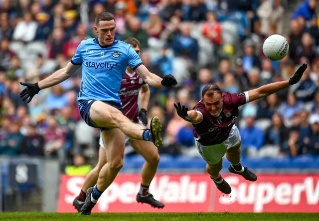 Brian Fenton of Dublin kicks a point despite the attention of John Maher of Galway