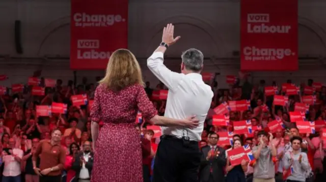 Sir Keir Starmer and his wife, the picture has been taken from behind them, facing the audience