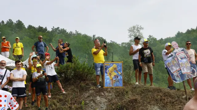 Spectators carry placards depicting the late Italian professional cyclist Marco Pantani