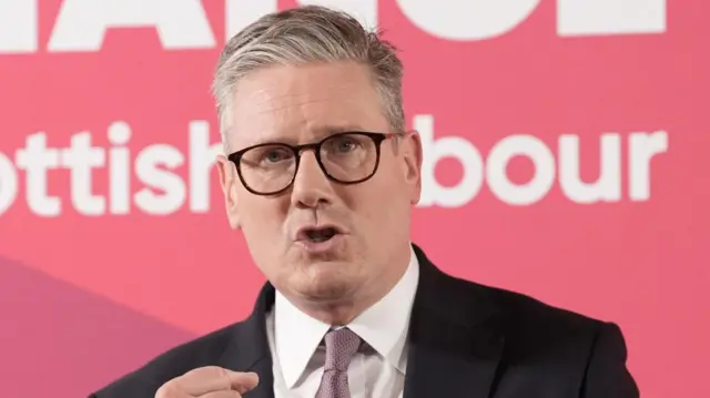 Starmer speaks in front of a red Labour party campaign backdrop