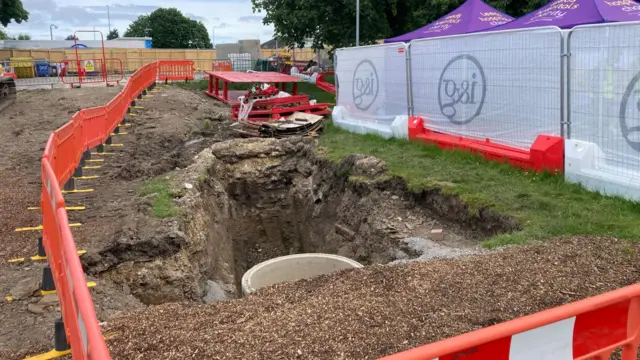 Ground dug up surrounded by orange plastic fencing