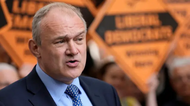 Ed Davey speaks in front of Lib Dem branding