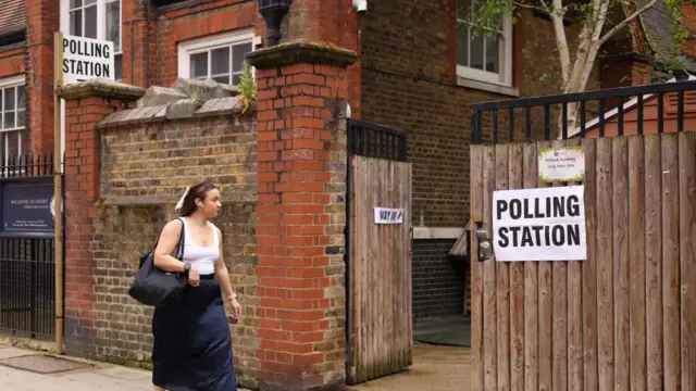 Woman walking past polling station (May 2025)