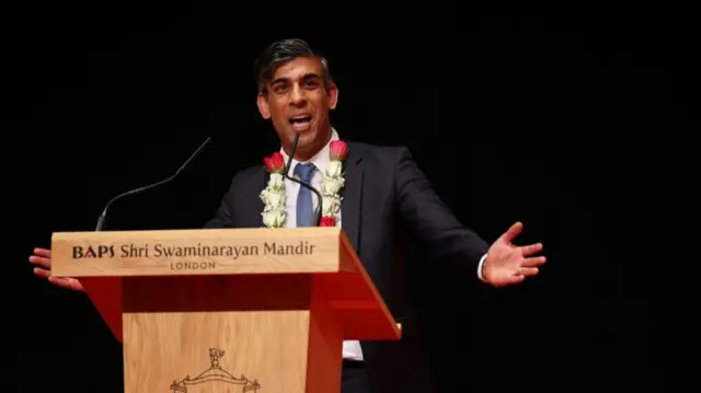 Rishi Sunak speaking into a microphone from behind a lectern