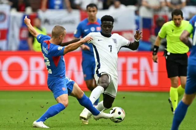 Slovakia's midfielder #22 Stanislav Lobotka (L) tackles England's forward #07 Bukayo Saka